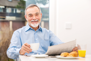 elderly holding a cup and newspaper